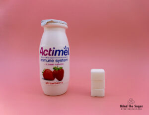 A photo of a bottle of Actimel with 3 cubes of sugar