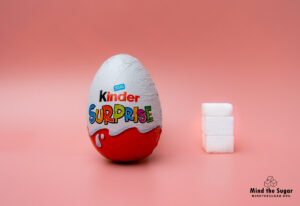 A photo of Kinder Surprise Egg with 2.6 cubes of sugar.