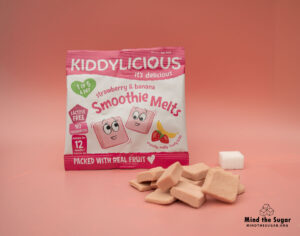 A photo of Kiddylicious Strawberry & Banana Smoothie Melts 6G pack with 1 cube of sugar.